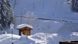 Paisaje nevado con una cabaña de madera y un banco.