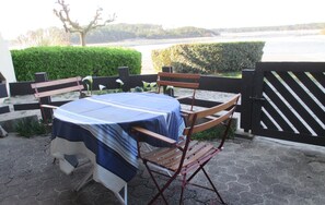 Tavolo apparecchiato all'aperto, con vista su un corpo d'acqua e vegetazione sullo sfondo.