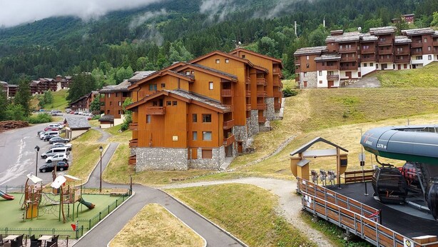 A mountain lodge with wooden architecture, a parking area, and a ski lift. - Divisible studio + mezzanine, ski-in/ski-out, sleeps 5, Valmorel (Valmorel)