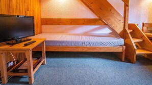 A small, cozy room with a bed, a television, and a wooden desk. - Divisible studio + mezzanine, ski-in/ski-out, sleeps 5, Valmorel (Valmorel)