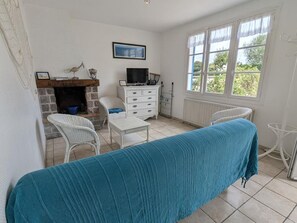 A room with a bed, a television, a fireplace, and a window with a view of greenery.