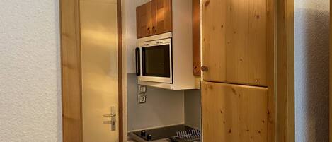A compact kitchen with wooden cabinets, a built-in microwave, and a sink.