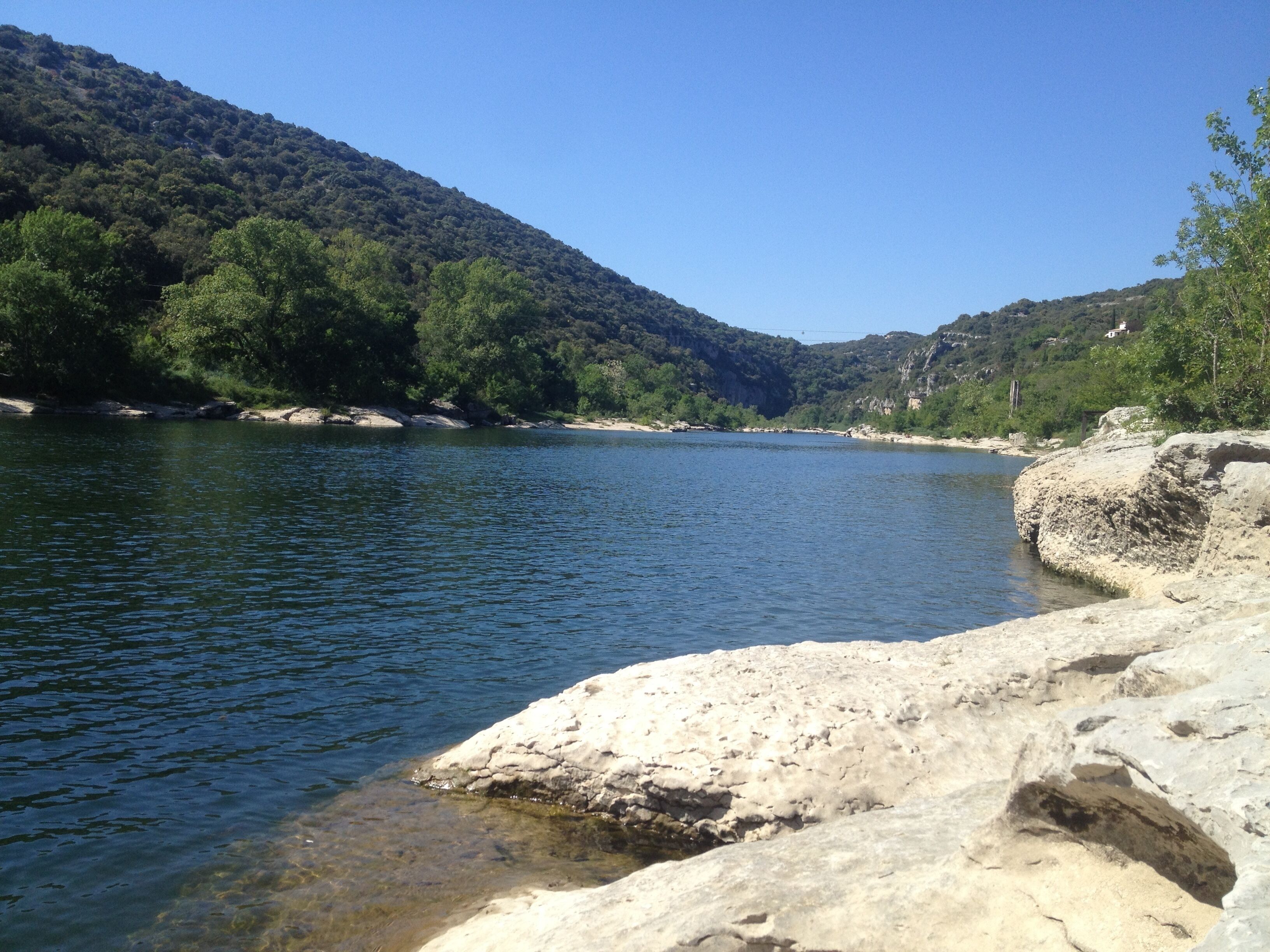 Un fiume con acque cristalline, circondato da terreno roccioso e vegetazione lussureggiante.