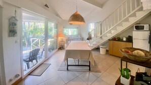 A spacious kitchen with a central island, a dining area with a table and chairs, and a staircase leading to an upper level.
