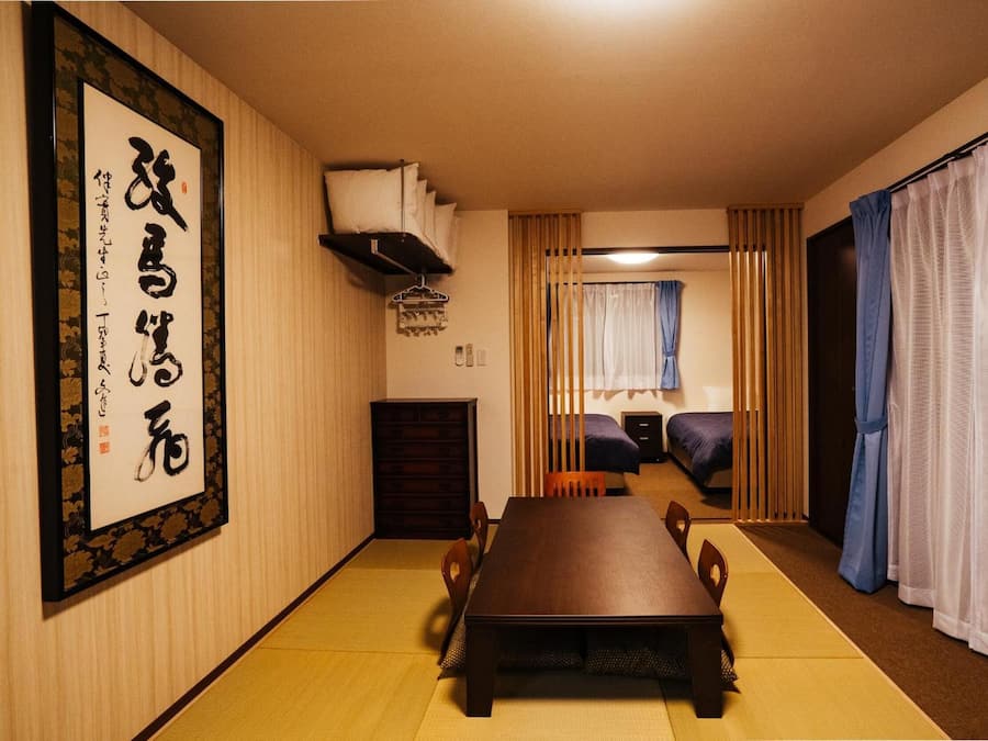 Um quarto japonês tradicional com tatames, uma mesa de madeira baixa e futons.