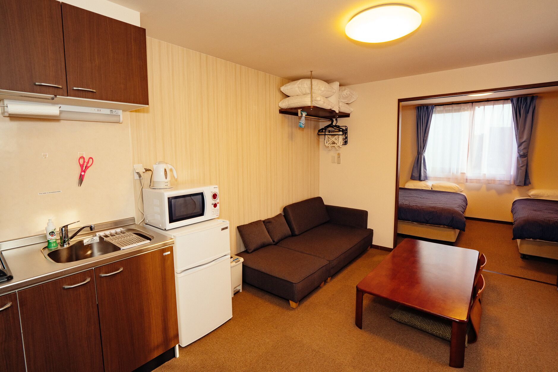 Quarto de hotel compacto com cozinha compacta, sofá, mesa pequena e cama.