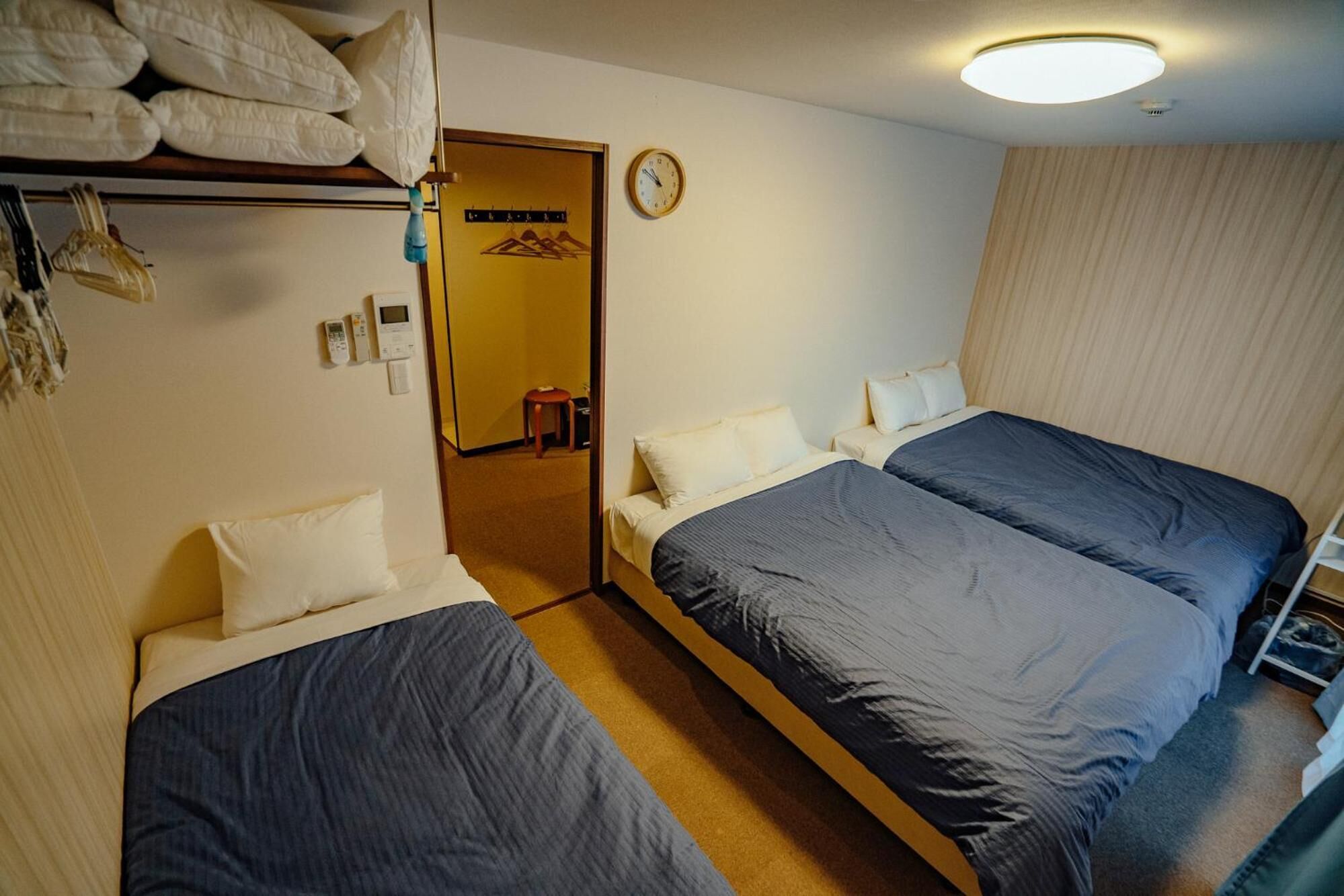 A hotel room with two beds, a wardrobe, a clock, and a mirror.