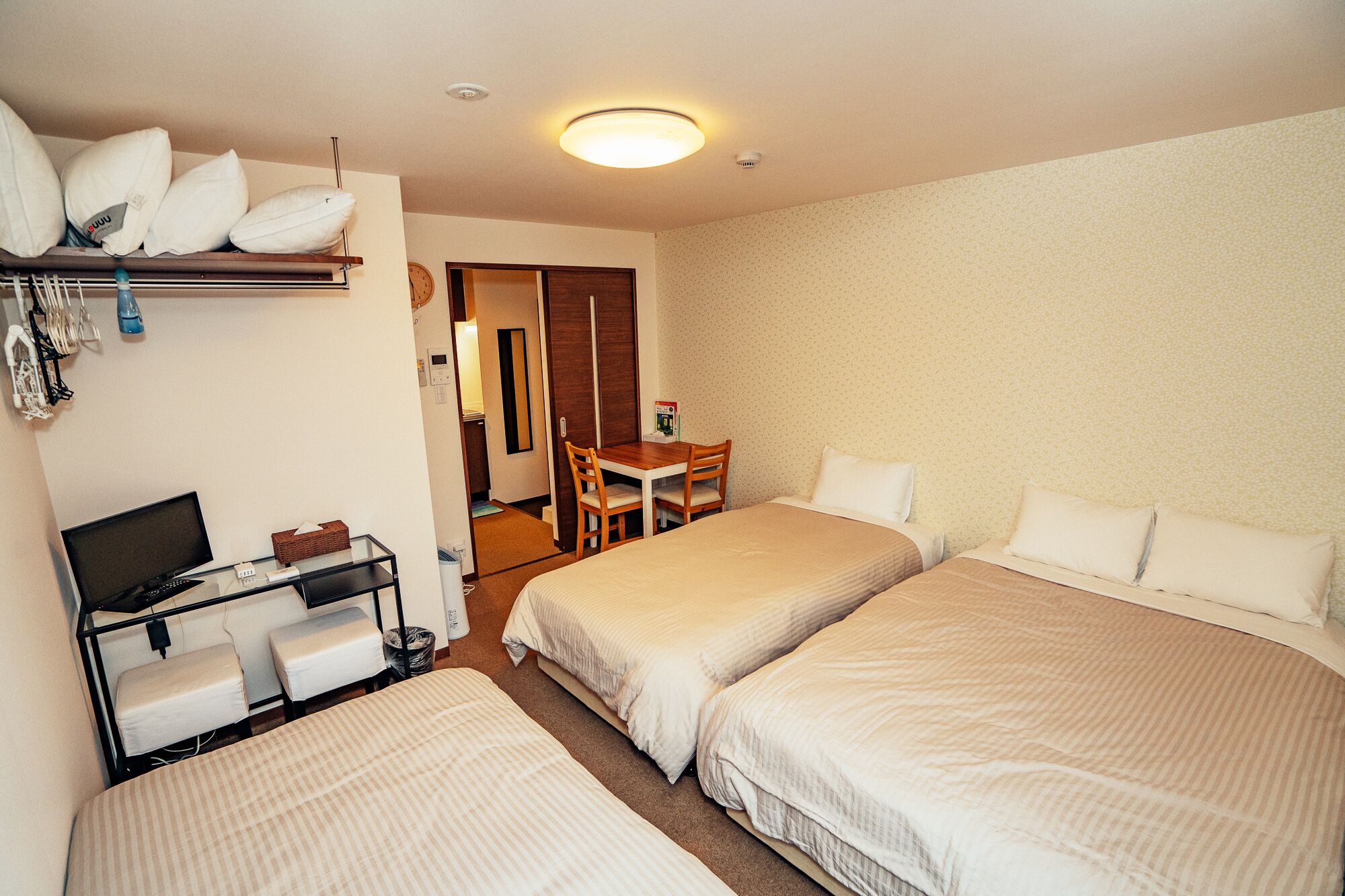 Hotellihuone, jossa on kaksi sänkyä, työpöytä tietokoneella ja tuoli.