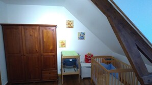 Una stanza con un'armadio in legno, una culla, una piccola scrivania e una sedia.