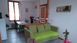Un soggiorno con un divano verde, un tavolino in vetro e un'area pranzo con tavolo e sedie.