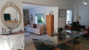 A spacious living area with a glass dining table, comfortable seating, a sofa, and a decorative mirror. - ESCALA, 5 minutes walk beach, VILLA STANDING160 habitab m2 / WIFI / WDM POOL  (L'Escala)