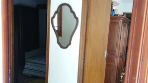 Ein Innenbereich mit einem Holztür, einem Spiegel an der Wand und einem Bett im angrenzenden Zimmer.
