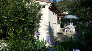 Ein Garten mit einem weißen Gebäude, einem Kiesweg und einem Tisch mit Stühlen.