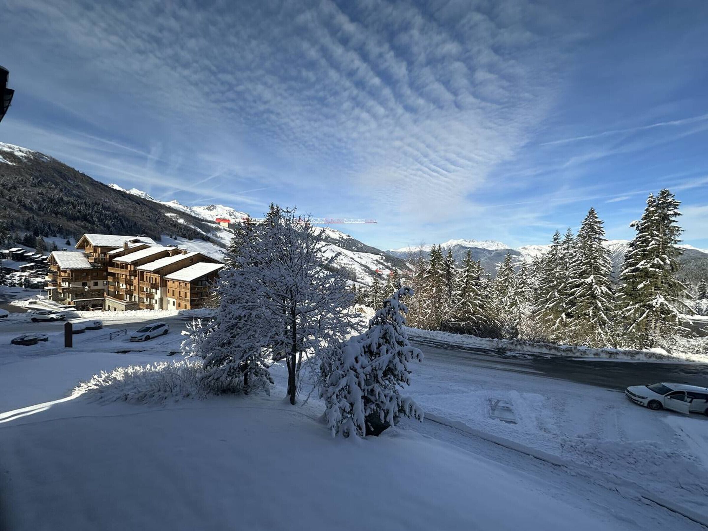 A snow-covered mountain resort with wooden buildings, a ski lift, and snow-laden trees.