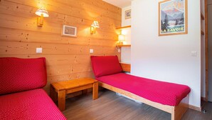 A room with two single beds, a wooden bench, and wall-mounted lights.