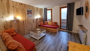Una habitación acogedora con pared de madera, un sofá, una mesa de centro y un televisor.