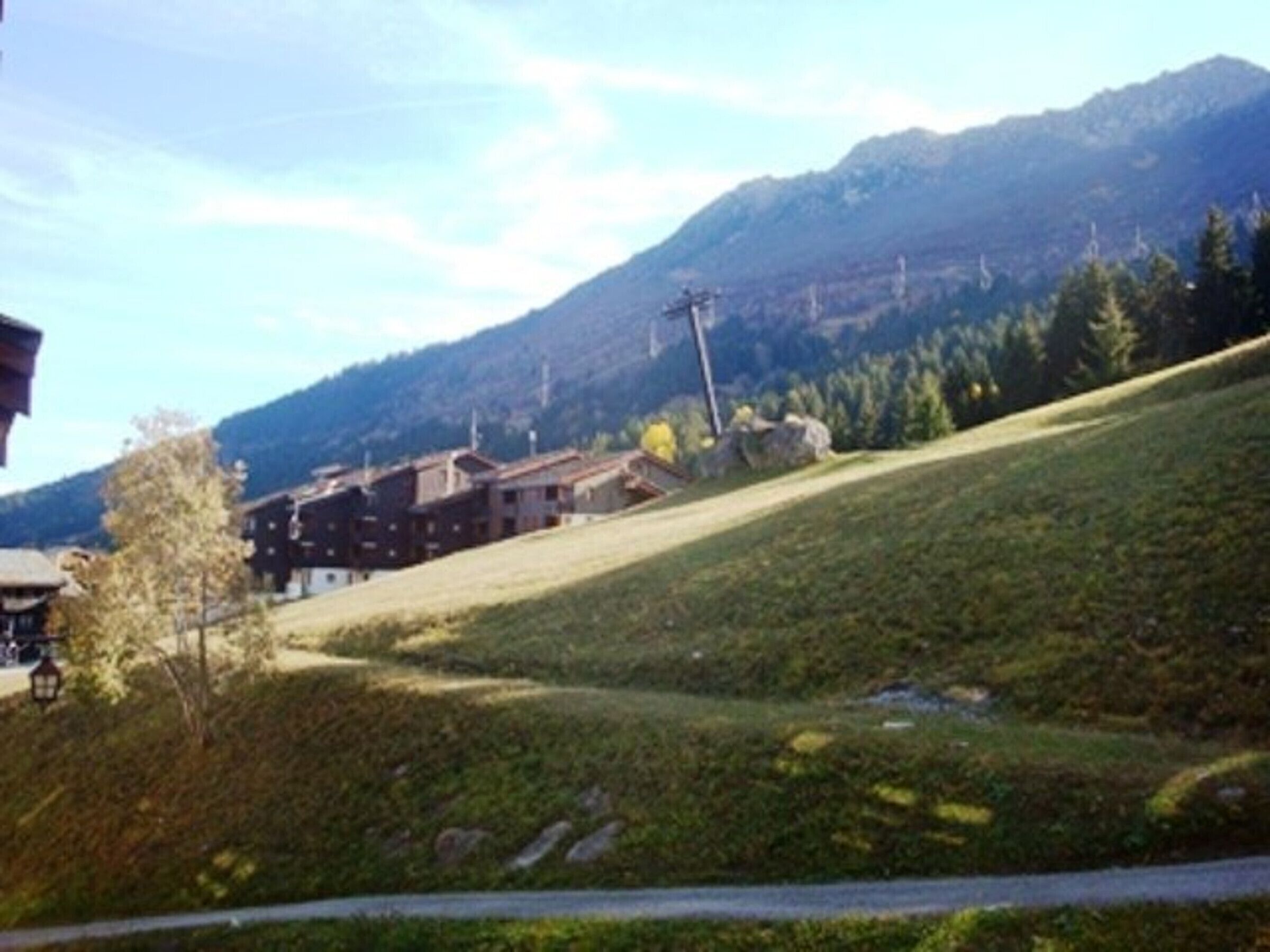 A hillside with buildings, a road, and a mountain in the background.