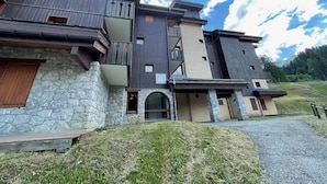 Un edificio de varios pisos con fachada de piedra, balcones de madera y cielo despejado.