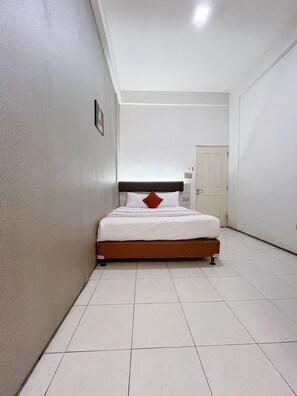 Een slaapkamer met een bed, een deur en een betegelde vloer.