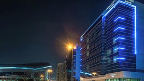 A modern hotel with a prominent 'Courtyard Marriott' sign, featuring a sleek, illuminated facade and a structured, multi-story design. - Courtyard by Marriott Al Barsha, Dubai (Dubai)