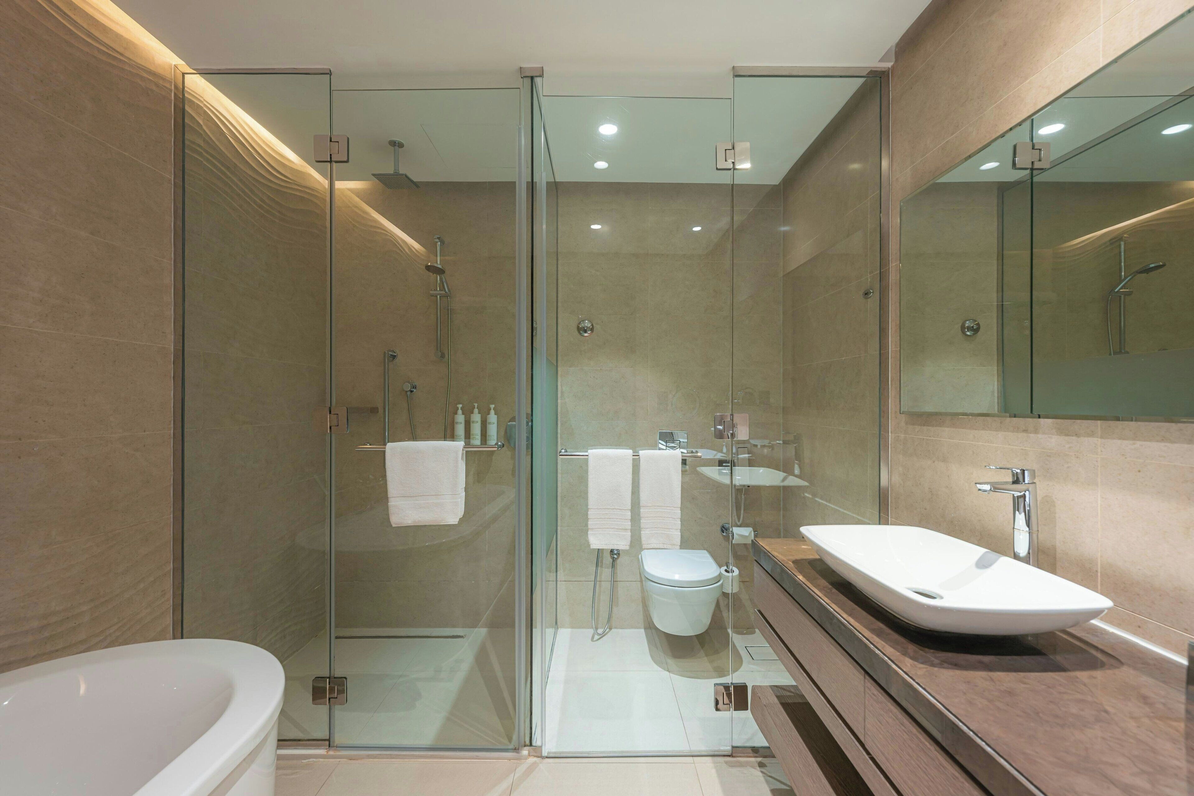 A modern bathroom with a glass-enclosed shower, a freestanding bathtub, and a large vanity with a vessel sink.