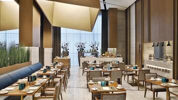 A modern dining area with long tables, chairs, and a central bar area.