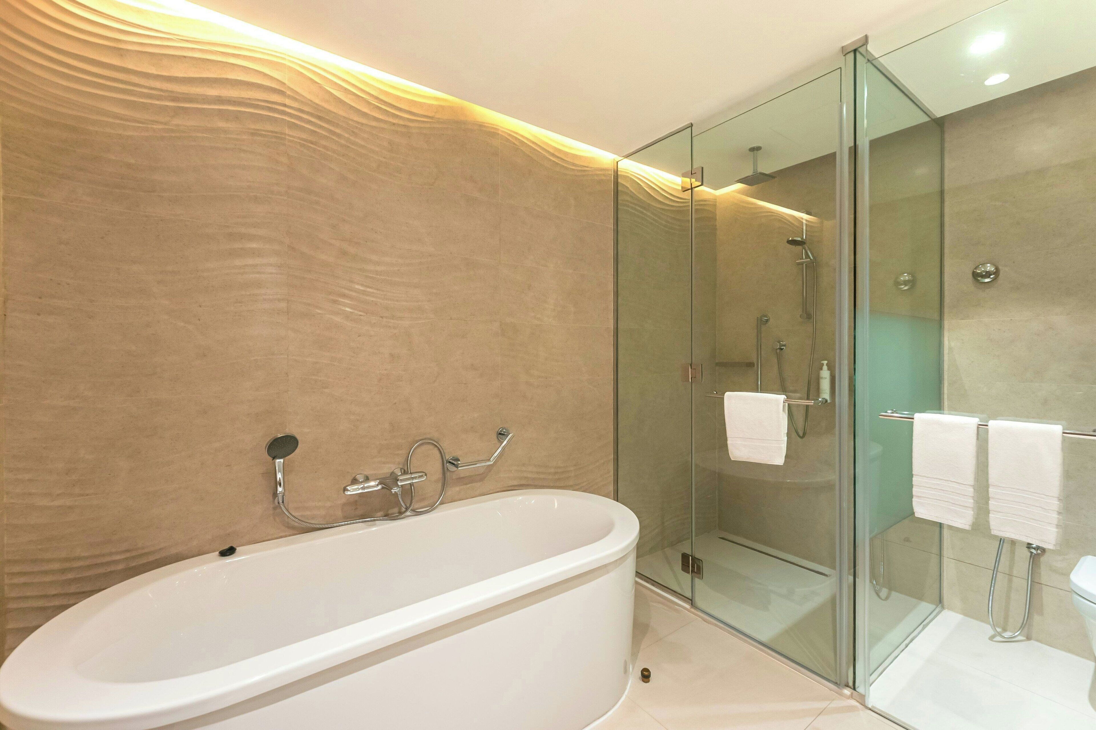 A modern bathroom with a freestanding bathtub, a glass-enclosed shower, and a toilet with a glass partition.