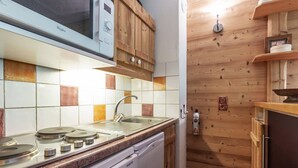 Eine kleine Küche mit Mikrowelle, Herd, Spüle und Holzausstattung.