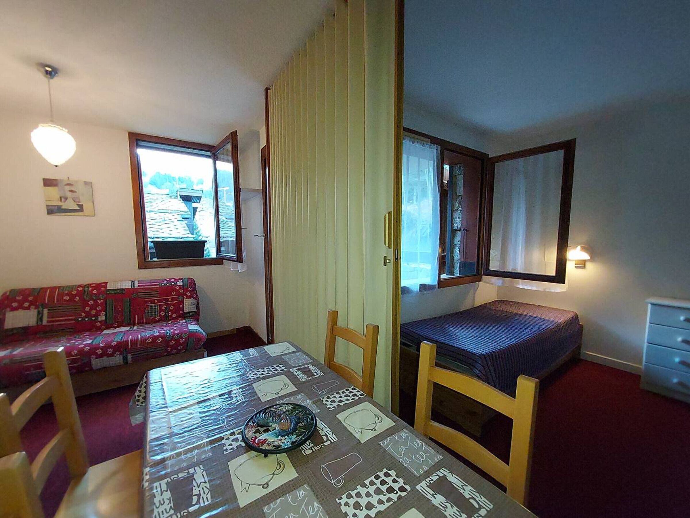 Ein kleiner, gemütlicher Raum mit einem Bett, einer Couch, einem Tisch und einem Fenster.
