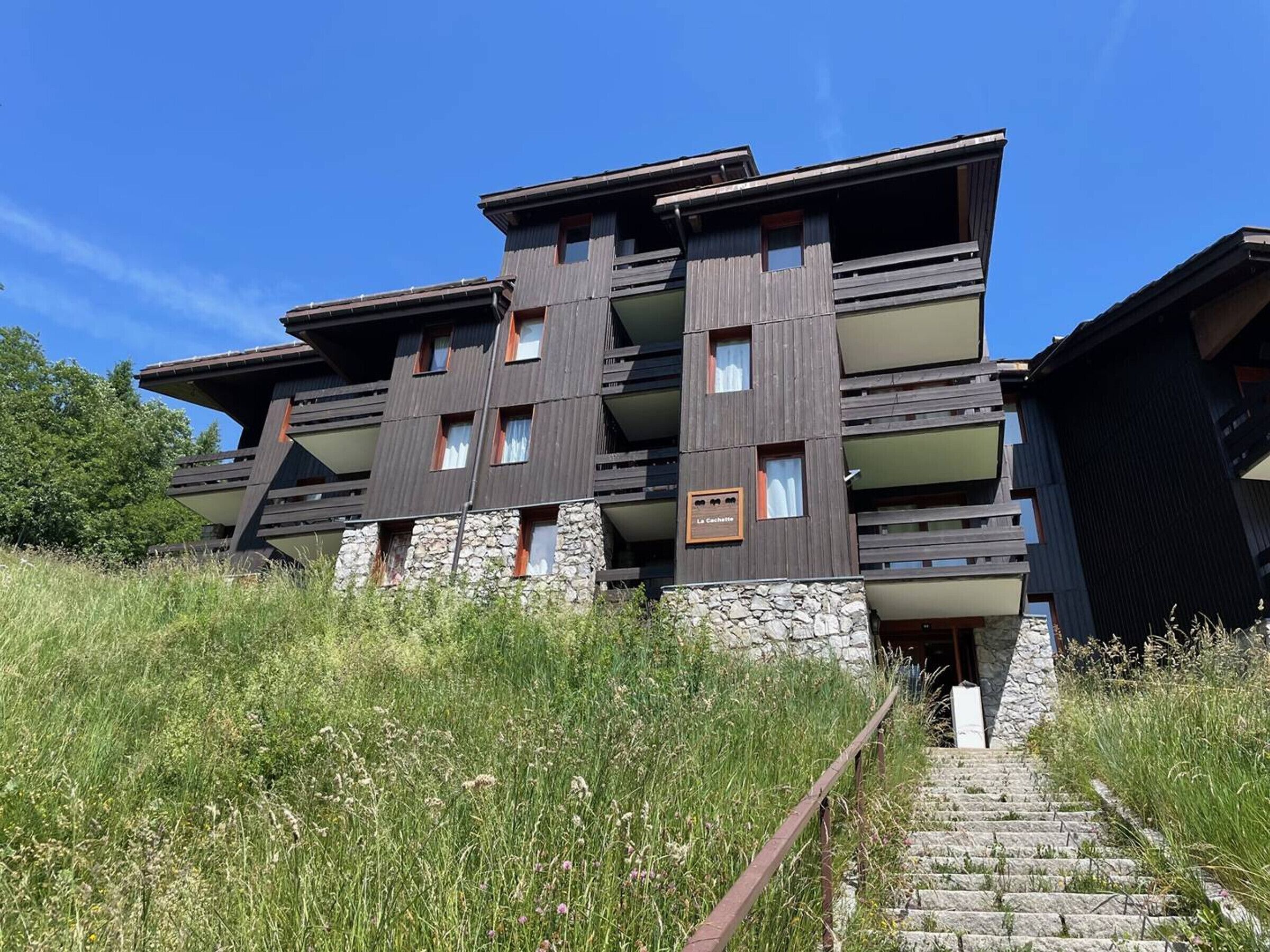 A modern multi-story building with a stone base and wooden upper floors.
