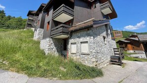 A modern chalet with a stone facade, multiple balconies, and a sign indicating it is a guesthouse. - Quiet apartment in Valmorel, pets allowed, 5 people (Valmorel)