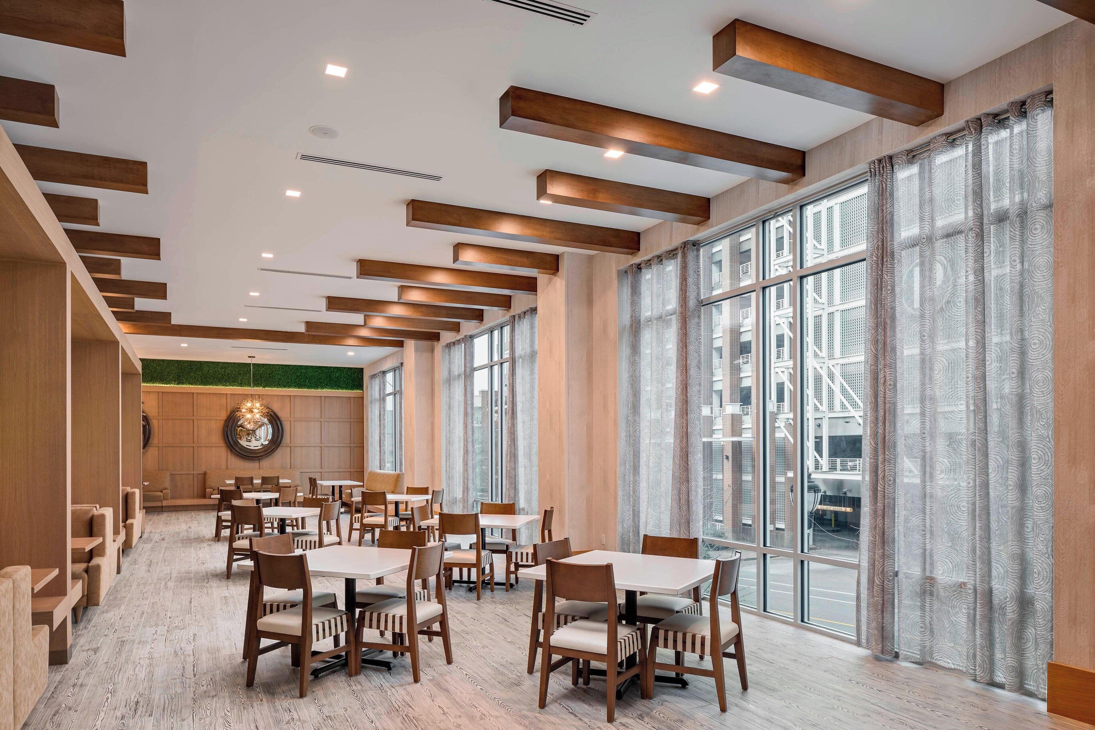 Un comedor espacioso con techos altos, vigas de madera y amplios ventanales que ofrecen vistas a la ciudad.
