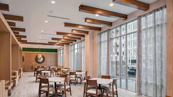 Un comedor espacioso con techos altos, vigas de madera y amplios ventanales que ofrecen vistas a la ciudad.