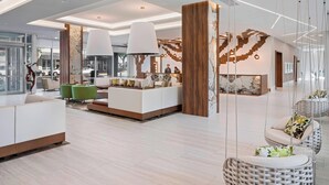 A modern hotel lobby with a reception desk, seating areas, and hanging chairs. - Residence Inn by Marriott Greenville Downtown (Greenville)