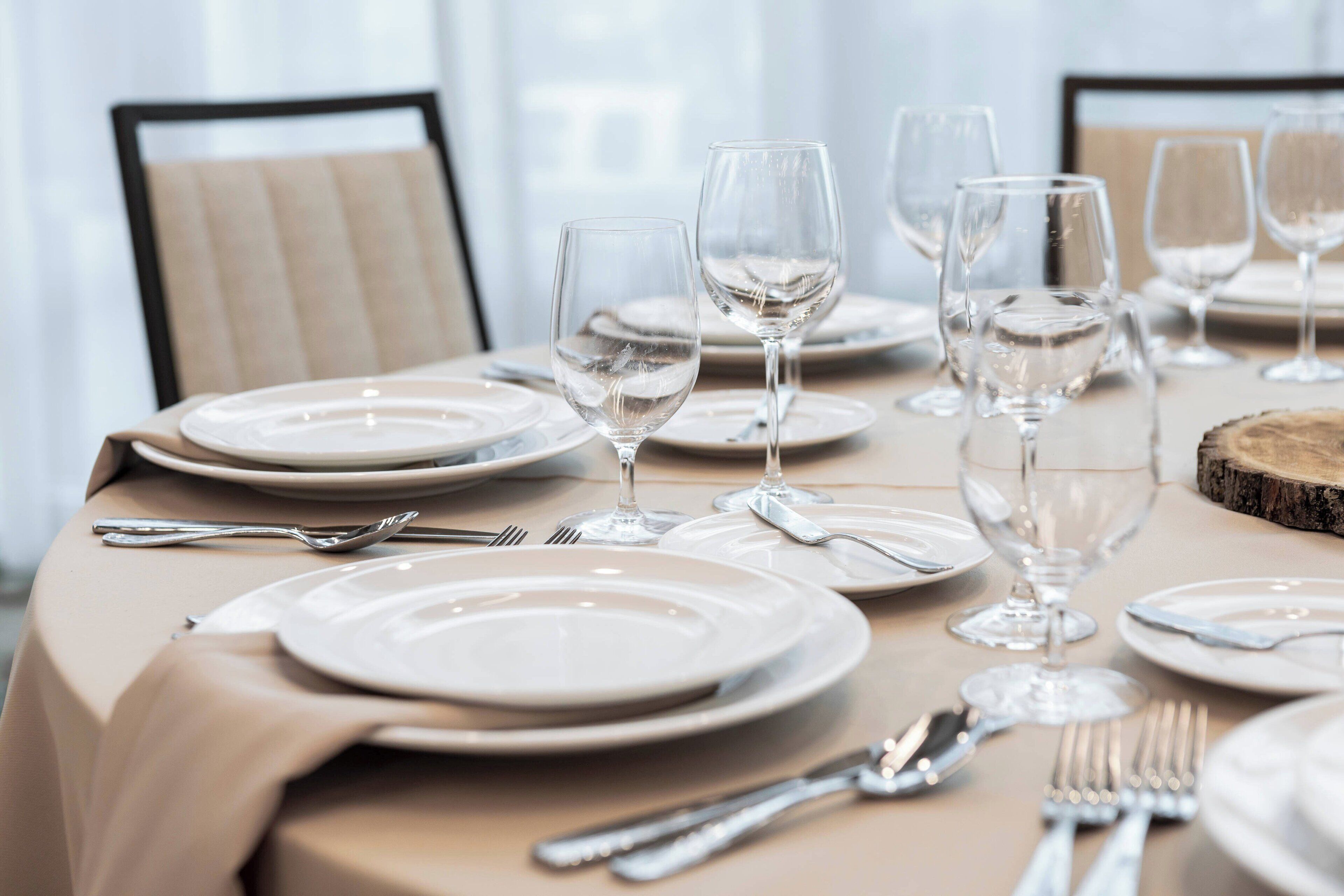 A dining table set with plates, cutlery, and wine glasses, indicating a formal dining arrangement.