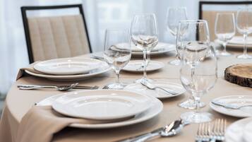 A dining table set with plates, cutlery, and wine glasses, indicating a formal dining arrangement.