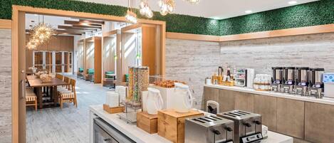 A modern kitchen area with a breakfast bar, toasters, and a coffee station.