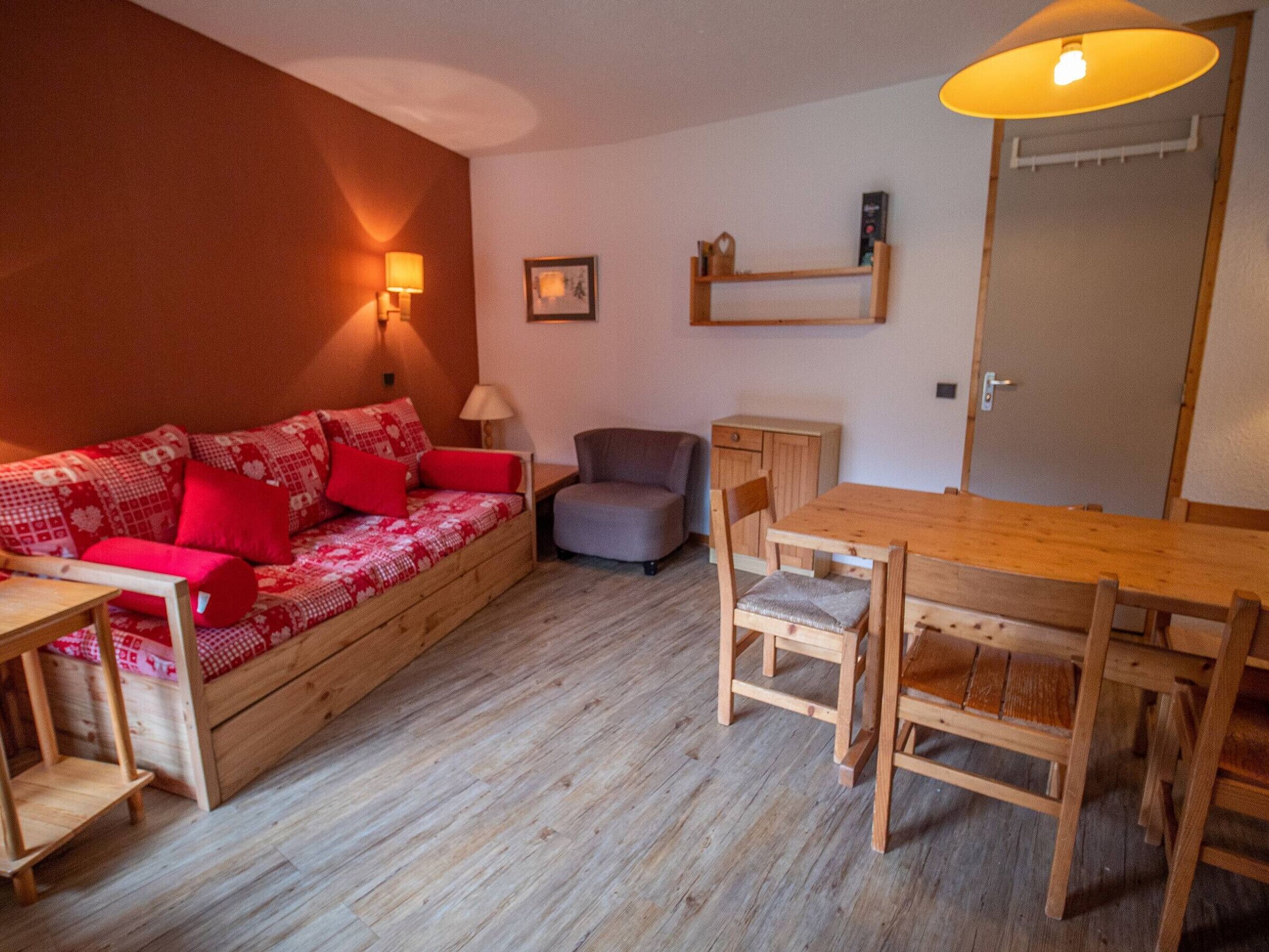 A cozy living room with a wooden sofa, a dining table, and chairs.