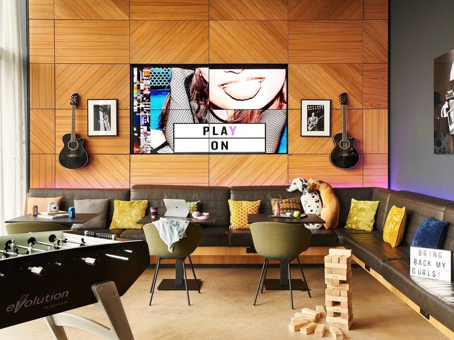 Una sala de estar moderna con una mesa de fútbol de mesa, un conjunto de sofás y un televisor mostrando el texto "PLAY ON".