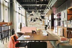 A modern workspace with a long table, multiple chairs, and a variety of office supplies.