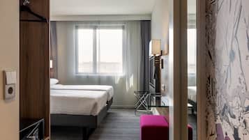 A hotel room with a bed, a desk, a chair, and a window with curtains.