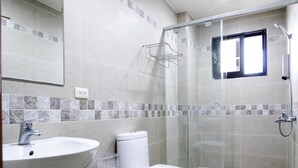 Une salle de bain équipée d’un lavabo, de toilettes et d’une douche à parois de verre.