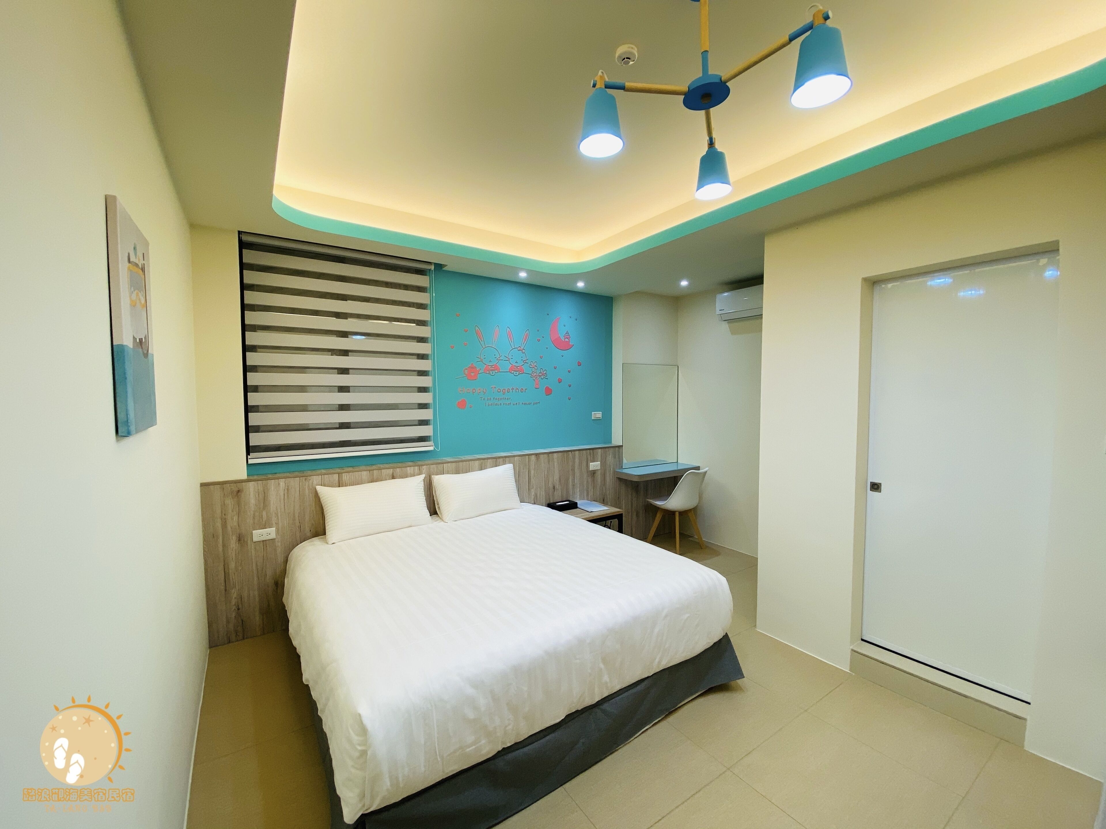 Habitación de hotel con una cama grande, un escritorio, una silla y un mural decorativo en la pared.
