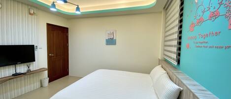 Un dormitorio con cama, televisión, lámpara en el techo y decoración en la pared.