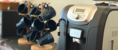 A coffee machine with a digital display and a portafilter, placed on a wooden coaster with multiple coffee cups.