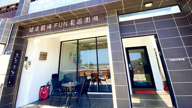 Un bâtiment moderne doté d’une entrée en verre, d’un espace détente visible avec des chaises et des tables, et d’une enseigne avec des caractères chinois.