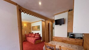 Ein gemütliches Zimmer mit Bett, Fernseher und einem Essbereich mit Stühlen und Tisch.