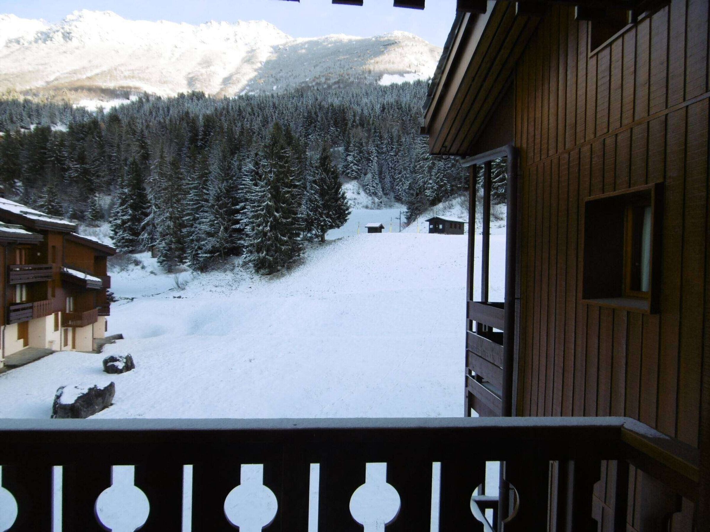 Un bâtiment en bois doté d’un balcon donnant sur un paysage montagneux enneigé.