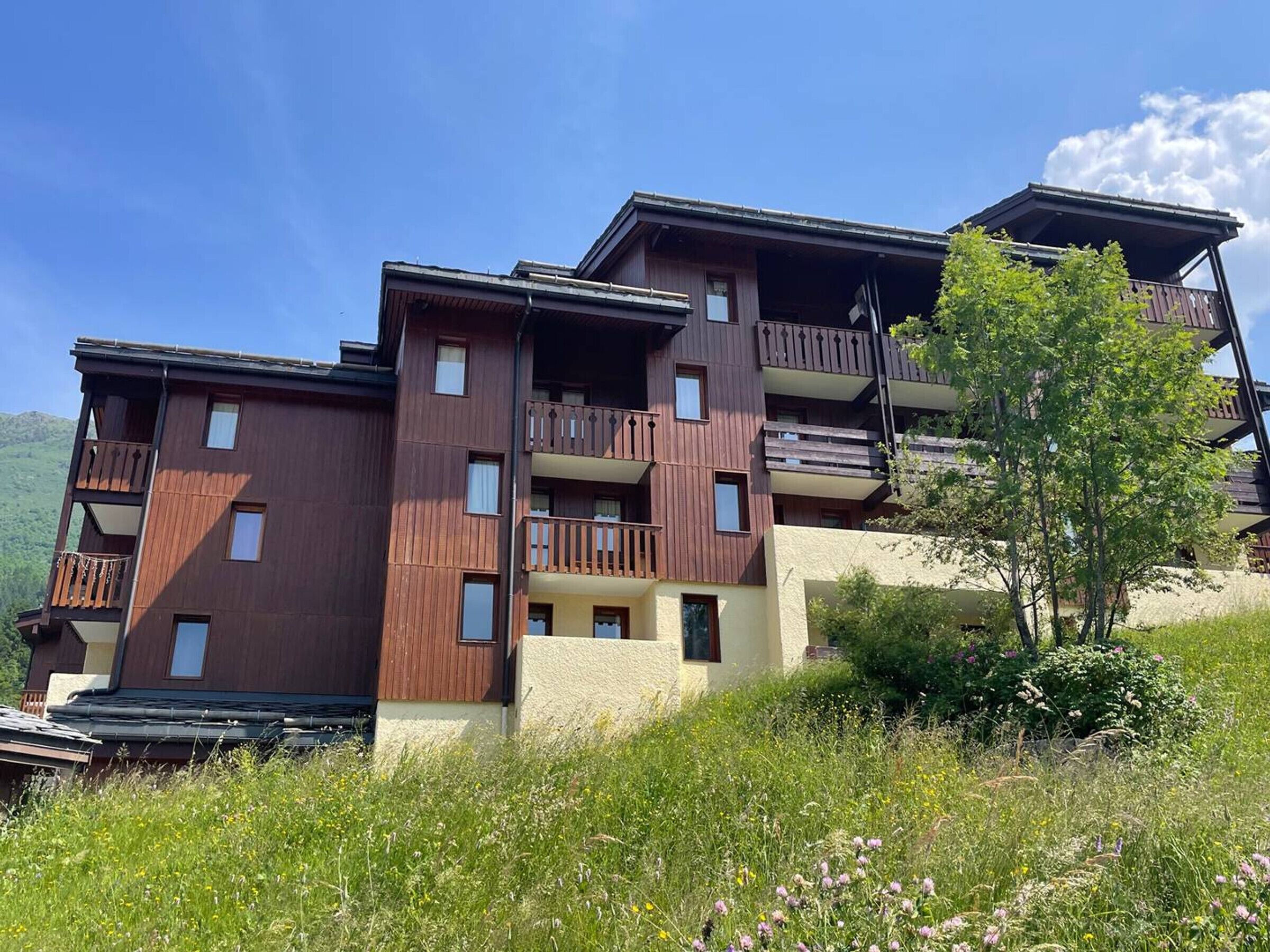 A multi-story building with balconies and a hillside setting.