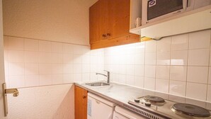 Una cocina compacta con microondas, un fregadero y estufa.
